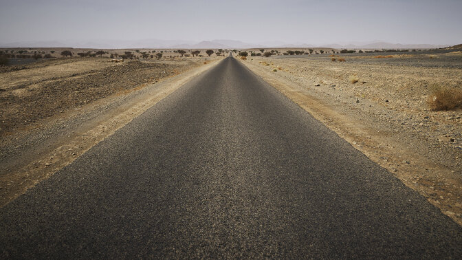 Larga carretera marroquí rodeada de desierto.