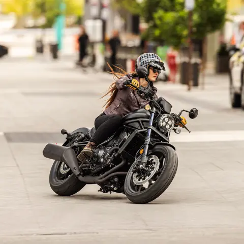 Imagen frontal de una modelo en una Honda CMX1100 en un entorno urbano.